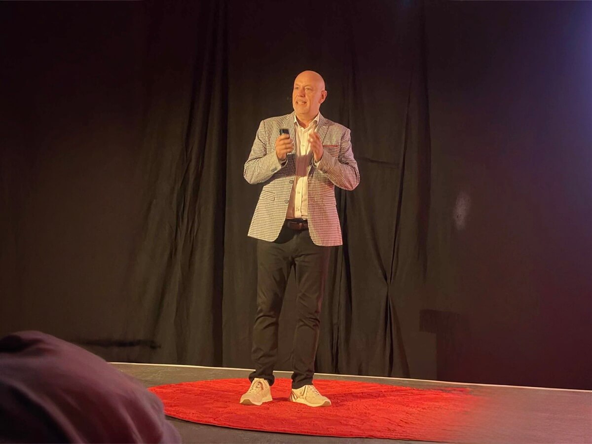 Andrew Scott delivering his TEDx Talk on stage at TEDxBristol, standing on the red circle